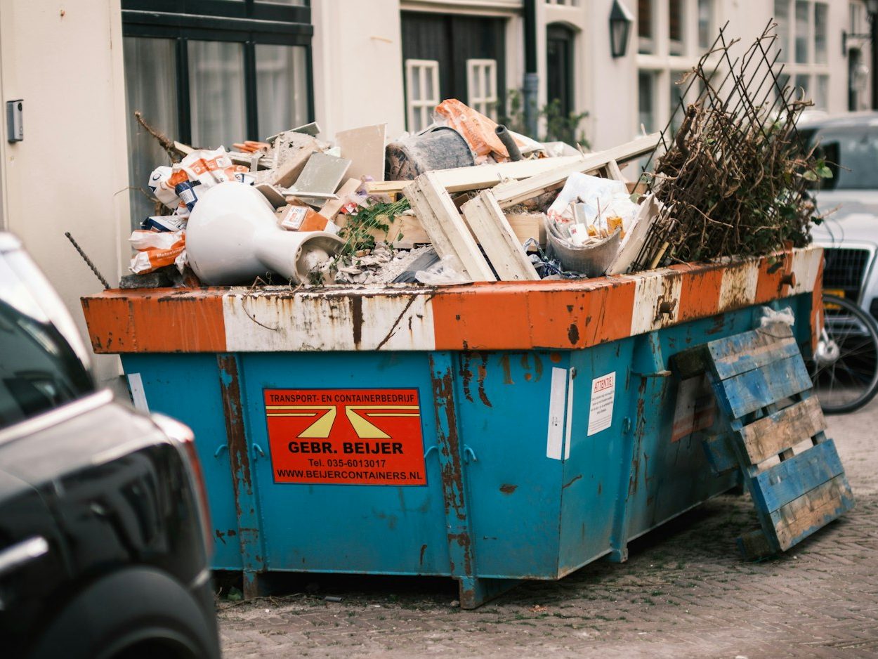 Blue open-top skip overflowing with renovation waste on a residential street